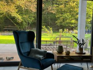 a living room with a blue chair and a table at Ferienhaus Waldbaden im Nationalpark Eifel- am Bach in Schleiden