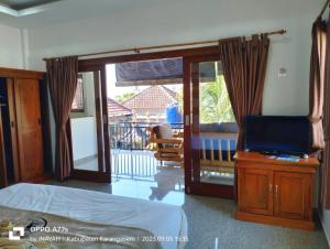 a bedroom with a bed and a television and a balcony at Pondok Wisata Balty Bali in Amed