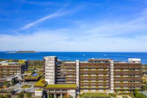 un grand bâtiment avec l'océan en arrière-plan dans l'établissement 1 Hotel Haitang Bay, Sanya, à Sanya