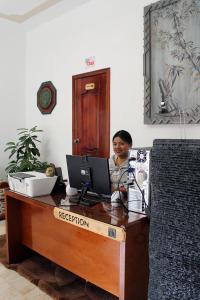 Chaska Hotel في اوتابالو: رجل يجلس في مكتب مع جهاز كمبيوتر محمول