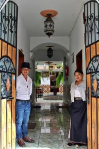 two people standing in the doorway of a house at Chaska Hotel in Otavalo