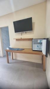 a television on a wall with a wooden bench at Tiki Bantayan Cebu Tourist Inn Inc in Pooc