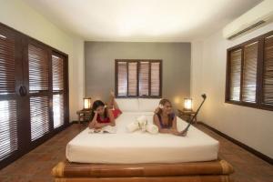 two girls sitting on a bed in a bedroom at Ananyana Leisure Beach Resort in Panglao