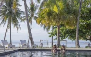 two women in a swimming pool with palm trees at Ananyana Leisure Beach Resort in Panglao Island