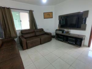 a living room with a couch and a flat screen tv at Luxo nas Ondas: Casa de Praia de Alto Padrão in São João da Barra