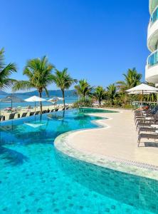 a swimming pool next to a beach with palm trees at Palace Praia Hotel in Florianópolis