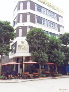 un hôtel avec des tables et des parasols devant un bâtiment dans l'établissement Lê Yên Hotel HN - by Bay Luxury, à Hanoï