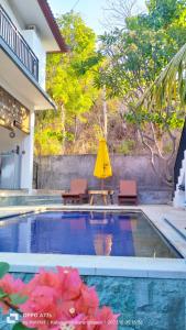 a pool with two chairs and a yellow umbrella at Pondok Wisata Balty Bali in Amed