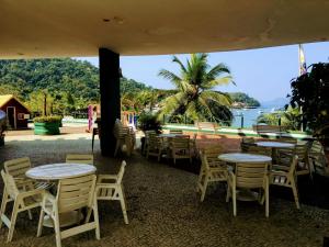 un patio con mesas y sillas y vistas al agua en Angra Inn Praia Grande, en Angra dos Reis