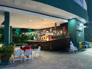 un hombre sentado en una mesa frente a un bar en Angra Inn Praia Grande, en Angra dos Reis