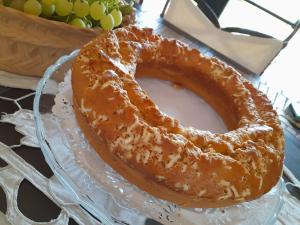 a bundt cake on a glass plate with a bowl of grapes at Villa Rossi in Polignano a Mare