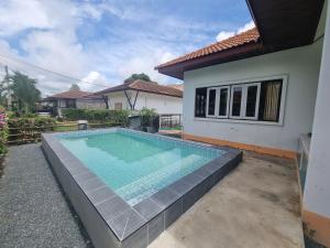 a swimming pool in front of a house at Mae Rampung Beach House Pool Villa in Rayong