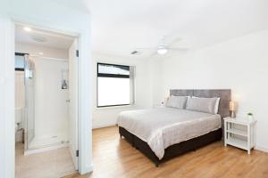 a white bedroom with a bed and a window at Agathas at Seacombe Gardens in Sturt