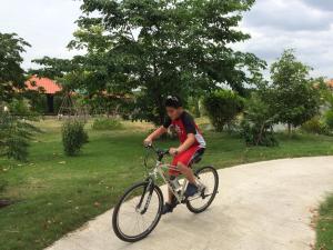 a young boy riding a bike on a path at Sripiamsuk Resort Bangkok in Pathum Thani