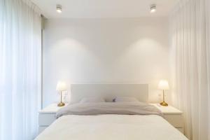 a white bedroom with a large bed with two lamps at Jaffa's Hideaway - Lux 2BR w/balcony and parking! in Tel Aviv