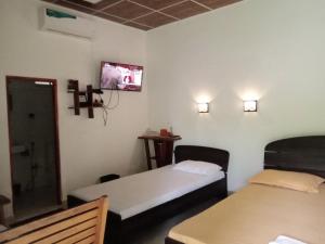a room with two beds and a tv on the wall at The Cascade Lodge in Embilipitiya