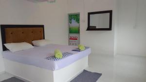 a white bedroom with a bed with two green pillows at Share Safari Family Bungalow in Udawalawe