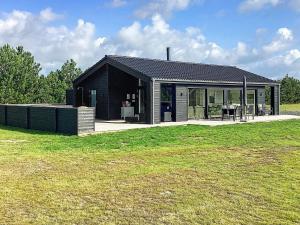 a black and white house with a grass field at Holiday home Væggerløse CCXVII in Bøtø By