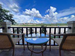 une table en verre sur un balcon avec vue sur l'eau dans l'établissement Chiangkhong Teak Garden Riverfront Onsen Hotel- SHA Extra Plus, à Chiang Khong