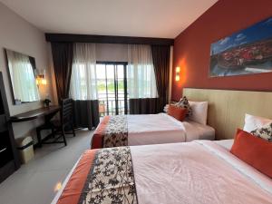 a hotel room with two beds and a desk at Chiangkhong Teak Garden Riverfront Onsen Hotel- SHA Extra Plus in Chiang Khong