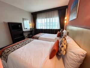a hotel room with two beds and a television at Chiangkhong Teak Garden Riverfront Onsen Hotel- SHA Extra Plus in Chiang Khong