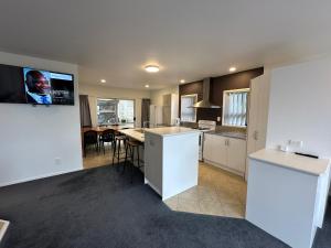a kitchen and dining room with a tv on the wall at Foreshore Mukies 2,0 in Ahipara