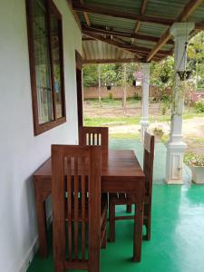 a wooden table and chairs on a porch at The Cascade Lodge in Embilipitiya