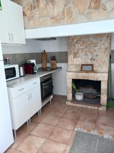 a kitchen with a stone fireplace in a kitchen at Casa dos pássaros in Carril