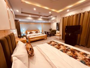 a hotel room with two beds and a television at Hotel Pinerock & Cafe, Mussoorie - Mountain View Luxury Rooms with open Rooftop Cafe in Mussoorie