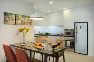 a kitchen with a table and chairs and a refrigerator at Somerset Central TD Hai Phong City in Hai Phong