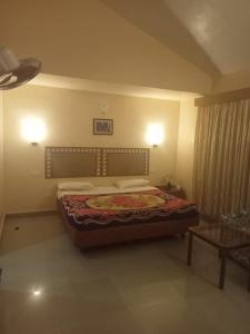 1 dormitorio con cama, mesa y luces en La Gabriell beach inn en Calangute