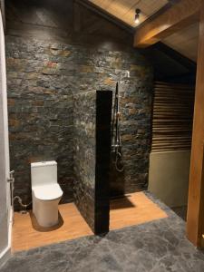 a bathroom with a toilet and a stone wall at Villa Amuntai with Pool & Jacuzzi in Dinalupihan
