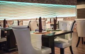 a dining room with a table and white chairs at Sharz Hotel in Buraydah