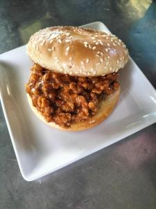 ein Sandwich auf einem weißen Teller mit einem Bagel in der Unterkunft Taakradan Valley Resort ท่ากระดานวัลเล่ย์ รีสอร์ท in Si Sawat