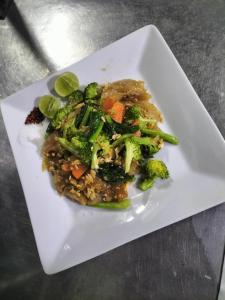 a white plate of food with broccoli and rice at Taakradan Valley Resort ท่ากระดานวัลเล่ย์ รีสอร์ท in Si Sawat