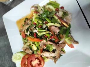 a white plate with a salad with meat and vegetables at Taakradan Valley Resort ท่ากระดานวัลเล่ย์ รีสอร์ท in Si Sawat