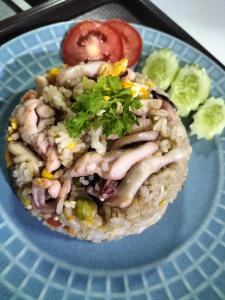 a plate of food with meat and rice and a tomato at Taakradan Valley Resort ท่ากระดานวัลเล่ย์ รีสอร์ท in Si Sawat