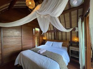 a bedroom with a bed with white sheets and curtains at Taman Asta Gangga by ecommerceloka in Silebeng