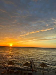 una puesta de sol en la playa con sombrillas y el océano en Maristella Marine Residense Hotel Apartment, en Odessa