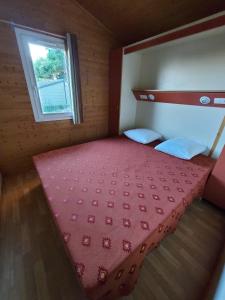 a large bed in a small room with a window at Cap d'Agde chalet vue sur la mer in Agde