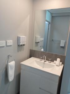 y baño con lavabo blanco y espejo. en Solomon Inn Motel Figtree, en Wollongong