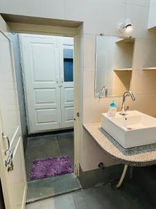 baño con lavabo y puerta con espejo en Atithya, en Udaipur