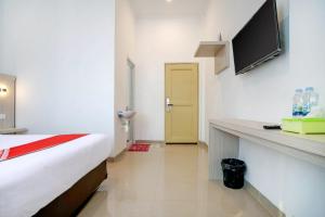 a hotel room with a bed and a flat screen tv at OYO Life 1299 Balcony Orange Homestay in Palembang