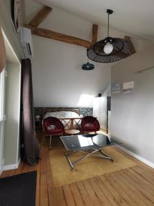a living room with a table and red chairs at Domaine de la Dolce Vita de Gaudreville la rivière in Gaudreville-la-Rivière