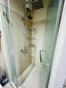 uma casa de banho com um chuveiro e uma porta de vidro em SHELL RESIDENCE em Manila