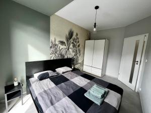 a bedroom with a bed with a black and white blanket at City Center Apartments z parkingiem in Bydgoszcz