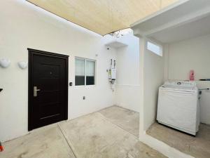 a laundry room with a black door and a washing machine at Mini Departamento Real del Country Playa Alberca in Manzanillo