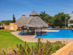 a resort with a swimming pool and a straw umbrella at Mini Departamento Real del Country Playa Alberca in Manzanillo