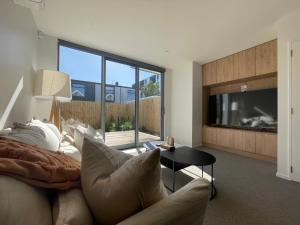 a living room with a couch and a tv at Inner City Luxury With Free Parking in Christchurch