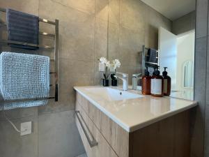 ein Badezimmer mit einem weißen Waschbecken und einem Spiegel in der Unterkunft Inner City Luxury With Free Parking in Christchurch